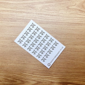 May include: A sheet of white paper with a repeating pattern of black airplane silhouettes. The paper has the text "lettr.digペーパー.co.uk" printed in the bottom right corner.