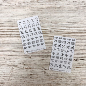 May include: Two sheets of stickers with black and white illustrations of fitness and kitchen icons. The fitness sheet includes icons for dumbbells, resistance bands, kettlebells, and more. The kitchen sheet includes icons for cooking utensils, food, and drinks. Both sheets have the text "lethbridgepaper.co.uk" at the bottom.