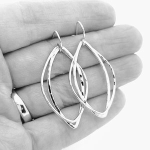 May include: Silver earrings with a double loop design. The earrings are made of a smooth, shiny metal and have a simple, elegant style.