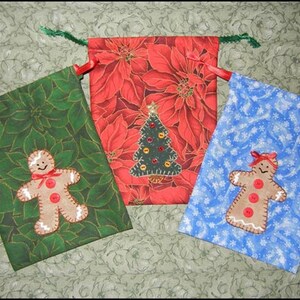 May include: Three Christmas gift bags with different designs. One bag is green with a gingerbread person, one is red with a Christmas tree, and one is blue with a snowflake pattern.