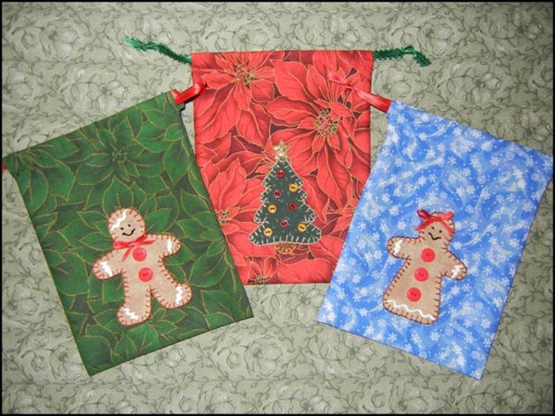 May include: Three Christmas gift bags with different designs. One bag is green with a gingerbread person, one is red with a Christmas tree, and one is blue with a snowflake pattern.