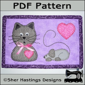 May include: A PDF pattern for a quilted wall hanging featuring a grey cat with a pink ribbon and a grey mouse with a pink heart. The background is a purple fabric with a swirl pattern.