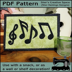 Pode incluir: Um padrão PDF para uma parede acolchoada com um design de notas musicais. O design inclui uma clave de sol e três notas musicais. O fundo é um tecido verde com um padrão de folhas. O texto "Sher's Creative Space (Sher Hastings Designs)" está na parte superior da imagem. O texto "Use with a snack, or as a wall or shelf decoration!" está na parte inferior da imagem.