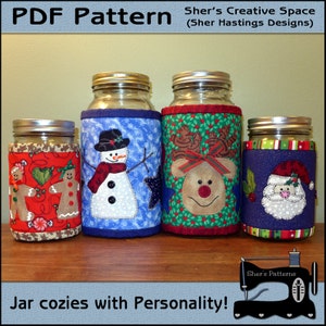 May include: Four Christmas-themed jar cozies with different designs: a snowman, a reindeer, a gingerbread man, and Santa Claus. The cozies are made of fabric and have a quilted appearance. The text "Sher's Patterns" is visible in the bottom right corner of the image.
