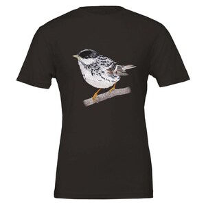 May include: Black t-shirt featuring a white and black bird illustration. The bird is perched on a branch and has a black head, white body, and black spots.