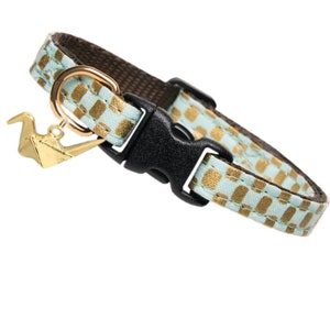 May include: A light blue and gold checkered cat collar with a gold origami crane charm.