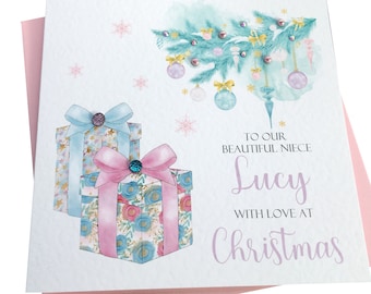 May include: A Christmas card with a watercolor illustration of a blue and pink Christmas tree with ornaments and presents. The text reads "To our beautiful niece Lucy with love at Christmas".