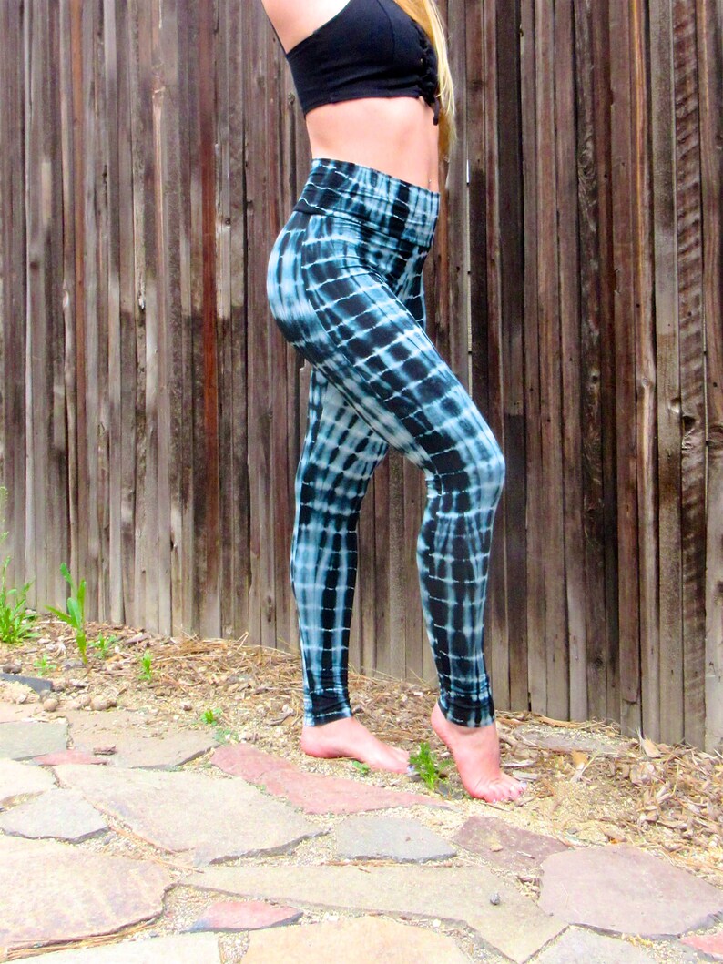 May include: Black and blue tie-dye leggings with a high waist. The leggings are made of a soft, stretchy fabric and are perfect for yoga, running, or everyday wear.
