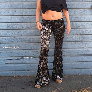 Op de afbeelding: Zwarte en witte bloemenprint bellbottom broek. De broek is gemaakt van een zachte, doorschijnende stof en heeft een wijde pijp.