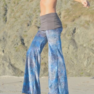 May include: A woman wearing a black sports bra and blue and white tie-dye flared pants. The pants have a wide leg and a high waist.