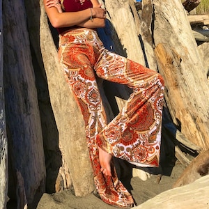 May include: A woman wearing a red crop top and wide-legged pants with a paisley print. The pants are a vibrant orange, white, and brown.
