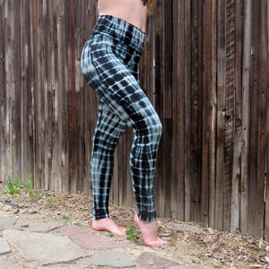 May include: Black and white tie-dye leggings with a checkered pattern. The leggings are fitted and have a high waist.
