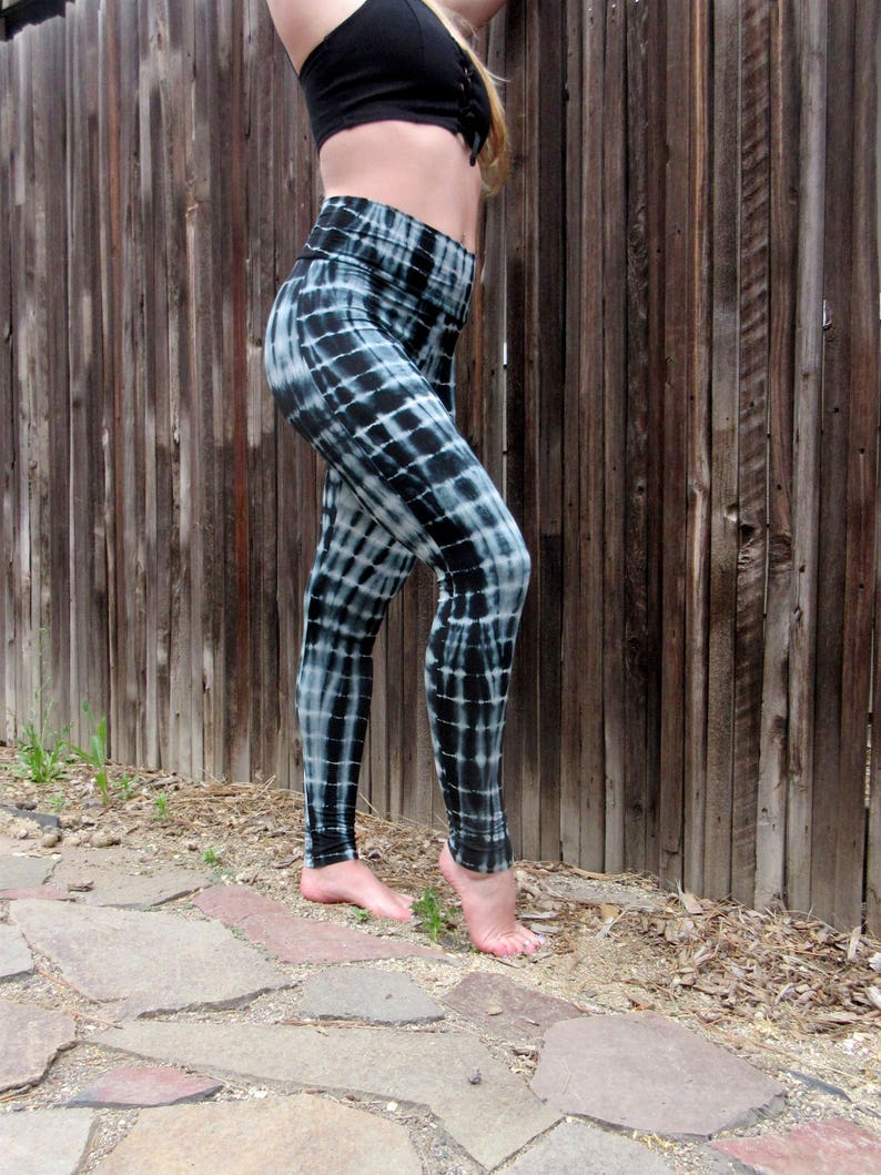 May include: Black and white tie-dye leggings with a checkered pattern. The leggings are fitted and have a high waist.