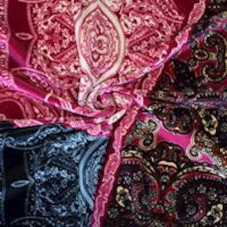 May include: A pink, black, and blue paisley patterned fabric with a white design. The fabric is soft and flowing.