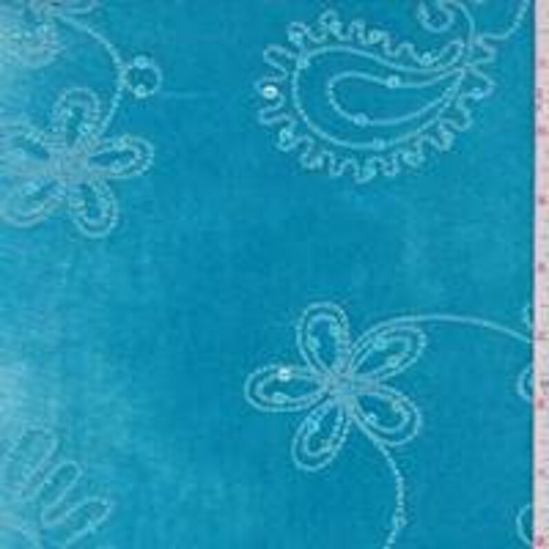Op de afbeelding: Tealblauwe stof met een wit paisley- en bloemenontwerp. Het ontwerp is omrand met pailletten.
