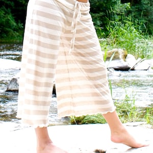 May include: A pair of white and beige striped wide-leg pants with a drawstring waist.