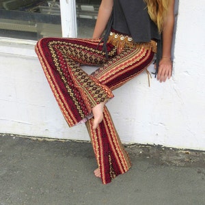 May include: A pair of red, black, and gold patterned bell bottom pants. The pants have a wide leg and a high waist. The pants are made of a soft, comfortable fabric.