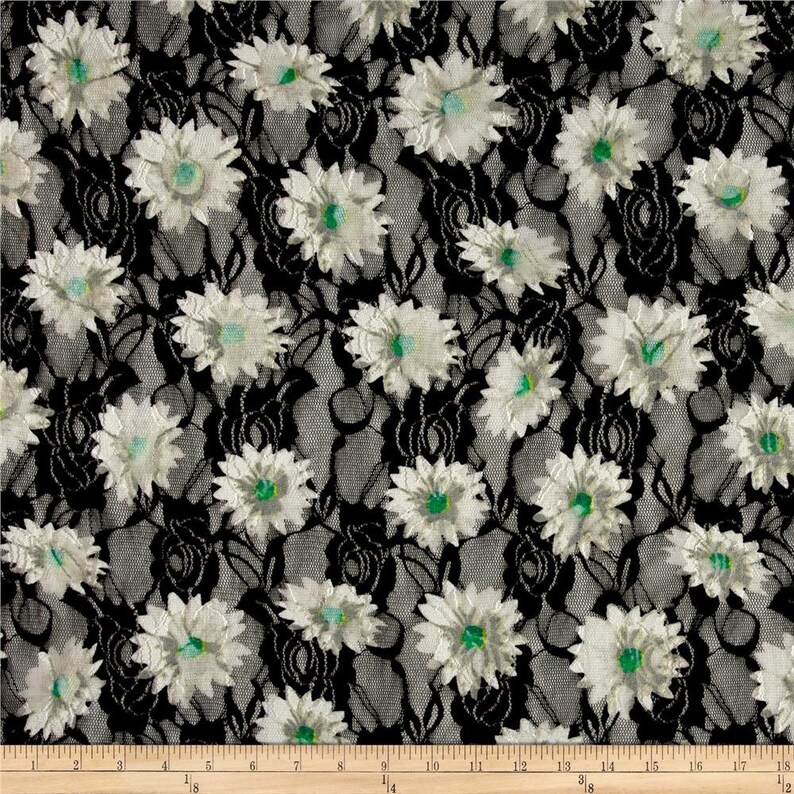 May include: Black lace fabric with a white floral pattern. The flowers have a green center.