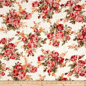 May include: White fabric with a floral pattern featuring red and pink roses. The fabric has a lace-like texture.