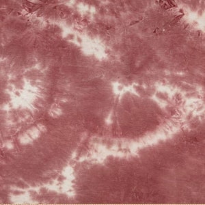 May include: A close-up of a red and white tie-dye fabric. The fabric has a swirling pattern of red and white.