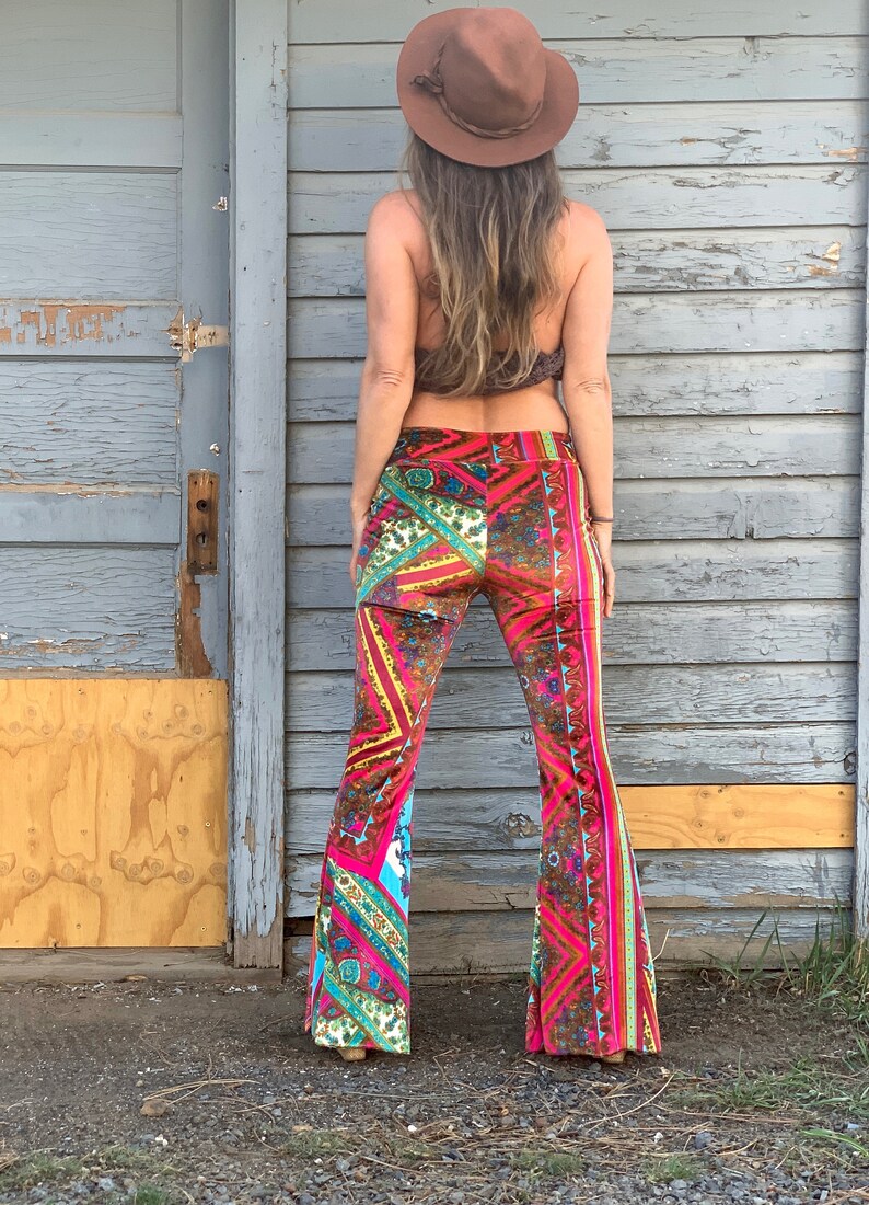 May include: A pair of wide-leg, bell-bottom pants with a colorful, geometric pattern. The pants are made of a soft, velvet-like fabric and have a high waist. The pants are pink, brown, yellow, blue, and green.