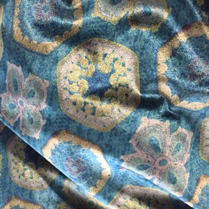 May include: Blue fabric with a repeating pattern of gold and pink floral designs. The fabric has a textured, velvet-like surface.