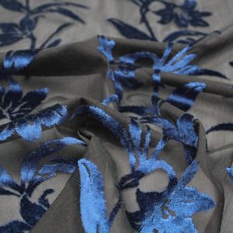 May include: Blue velvet floral design on a black sheer fabric. The fabric is soft and luxurious, perfect for creating unique garments or home decor.