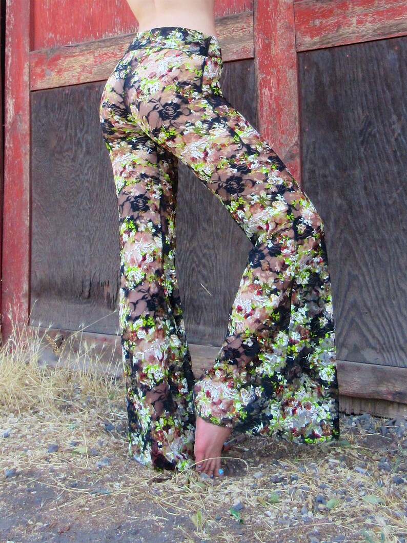 May include: Black lace pants with a floral print in shades of green, brown, and white. The pants have a wide leg silhouette.