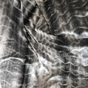 May include: A close-up of a white and gray tie-dye fabric with a wavy pattern.