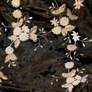 Pode incluir: Tecido de veludo preto com desenhos florais bordados em branco. O tecido tem uma textura macia e felpuda.