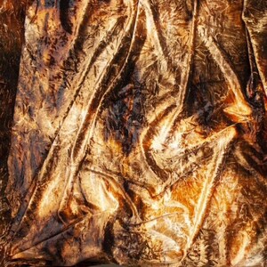 K&ouml;nnte beinhalten: Nahaufnahme eines goldenen, gekr&auml;uselten Samtstoffes mit einer strukturierten, zerknitterten Oberfl&auml;che.