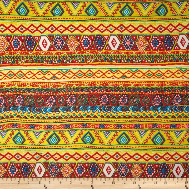 May include: Multicolored fabric with a repeating geometric pattern. The pattern features red, yellow, blue, green, and white colors. The fabric has a tribal or ethnic design.