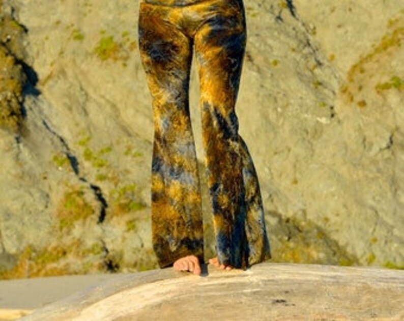 K&ouml;nnte beinhalten: Eine weite, ausgestellte Hose in einem Batik-Muster mit Gelb-, Braun- und Blaut&ouml;nen.
