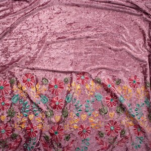 Pode incluir: Tecido de veludo esmagado rosa com detalhes florais bordados em tons de vermelho, amarelo, verde e azul.