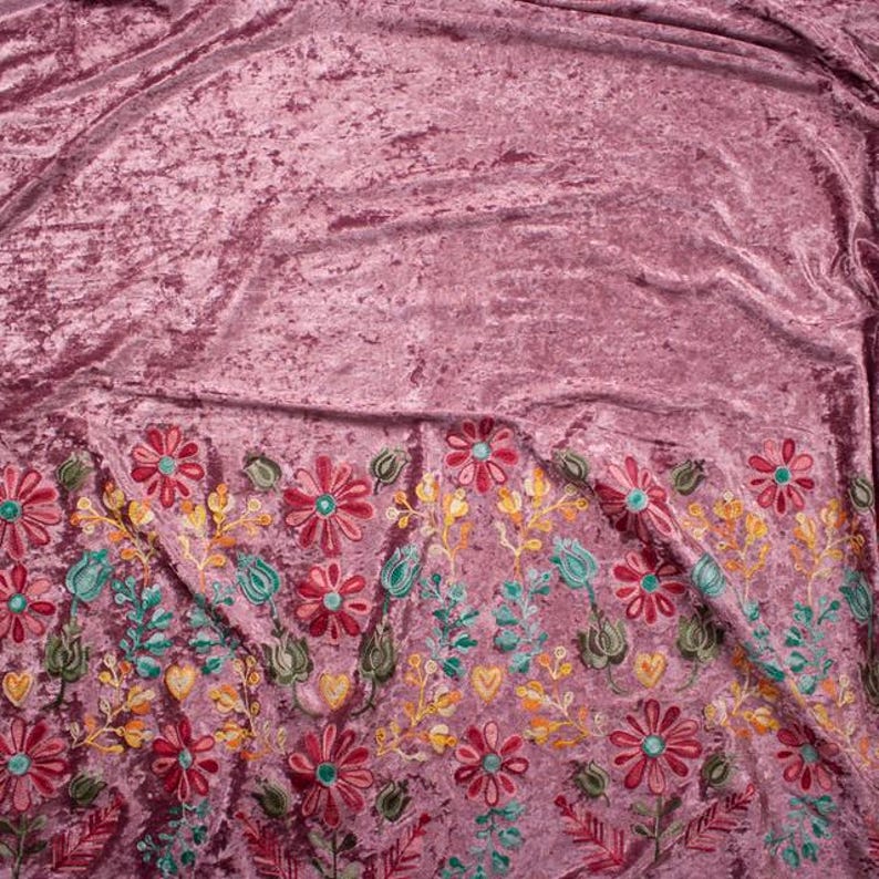Pode incluir: Tecido de veludo esmagado rosa com detalhes florais bordados em tons de vermelho, amarelo, verde e azul.