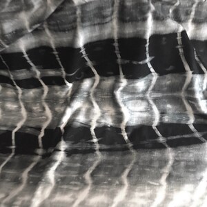 May include: Black and white fabric with a wavy, striped pattern. The fabric has a soft, flowing texture.