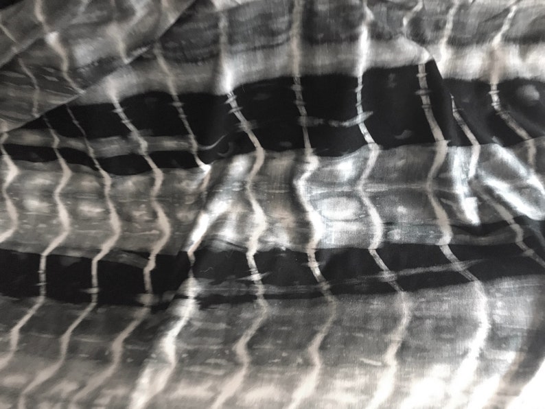 May include: Black and white fabric with a wavy, striped pattern. The fabric has a soft, flowing texture.