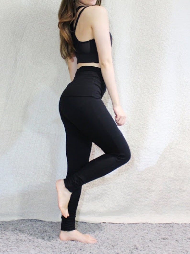 May include: A woman wearing a black sports bra and black leggings. The leggings have a high waist and are form-fitting.