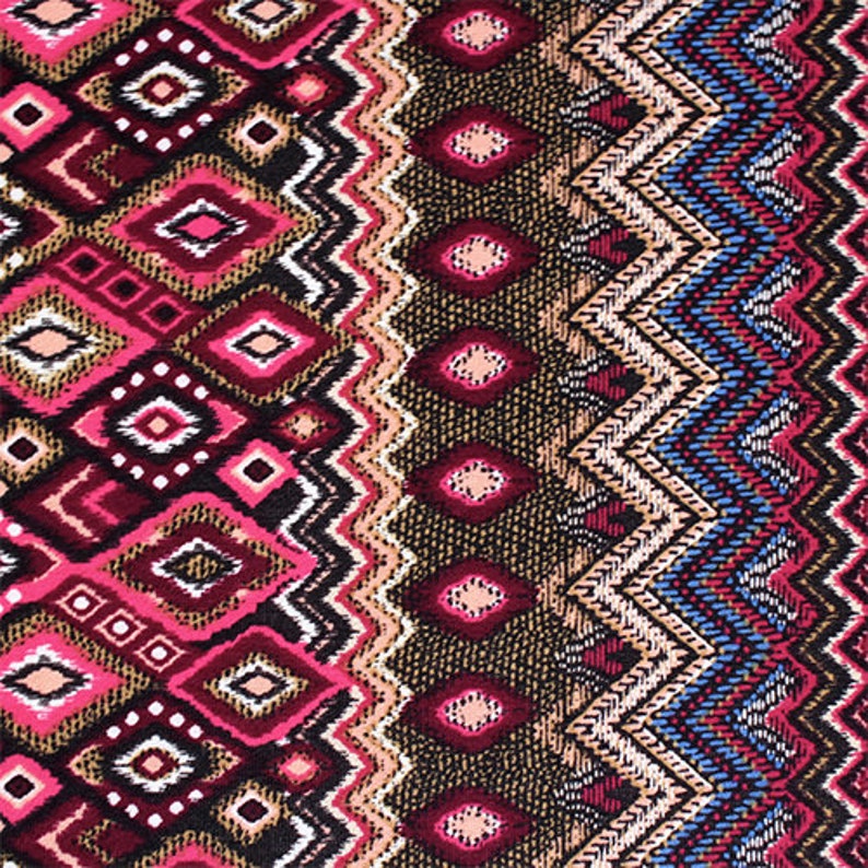 May include: A colorful fabric with a geometric pattern in shades of pink, brown, blue, and white. The pattern features a repeating diamond shape with a zig-zag border.