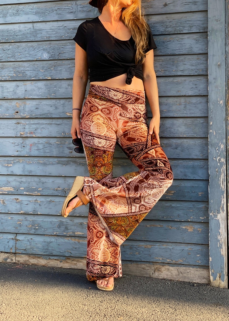 May include: A pair of wide-leg pants with a paisley print in shades of brown, orange, and green. The pants are made of a soft, velvety fabric and have a wide, flowing leg.