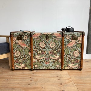 May include: Three vintage wooden storage trunks with floral patterned fabric covering. The fabric features a repeating pattern of birds, flowers, and leaves in shades of green, pink, and brown.