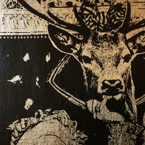 May include: A black and gold stag head with antlers, printed on a gold background. The stag is wearing a black collar.