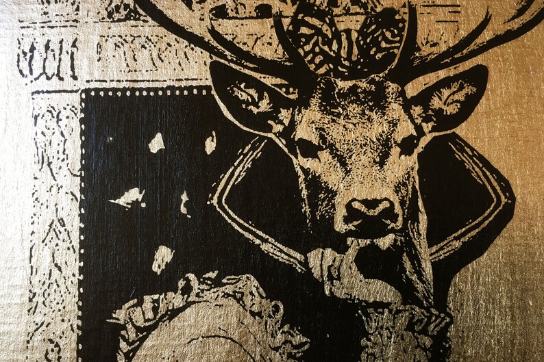 May include: A black and gold stag head with antlers, printed on a gold background. The stag is wearing a black collar.