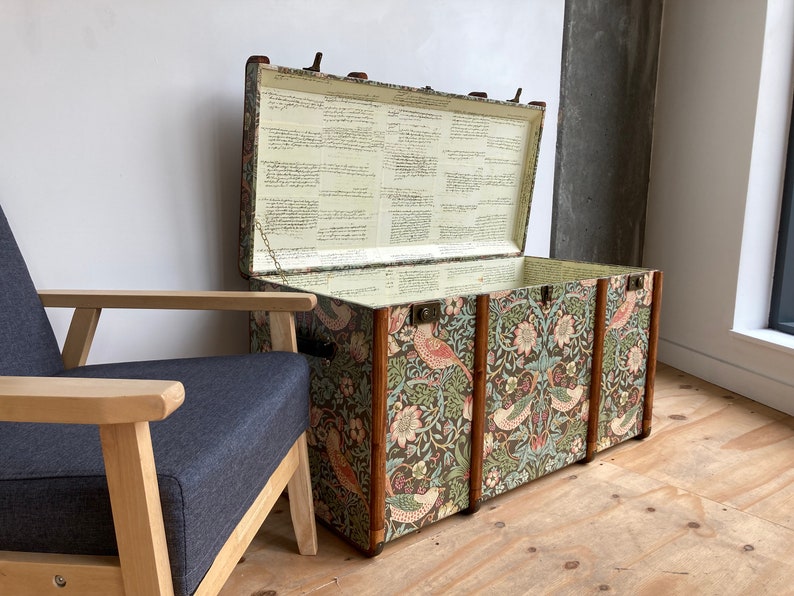 May include: A vintage floral patterned storage trunk with a wooden frame and brass hardware. The trunk is open and the inside is lined with white paper.