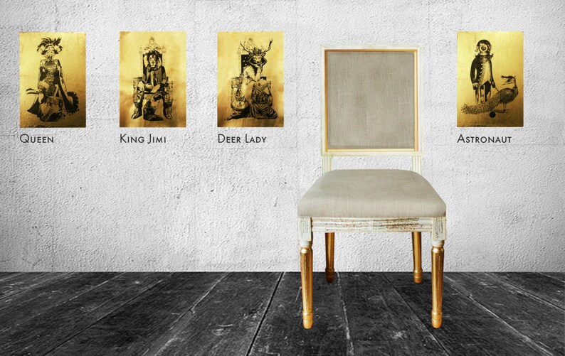 May include: Four framed black and white illustrations of people in costumes, with the titles "Queen", "King Jimi", "Deer Lady", and "Astronaut" below each image. A white chair with a beige cushion and gold legs sits in front of the wall.