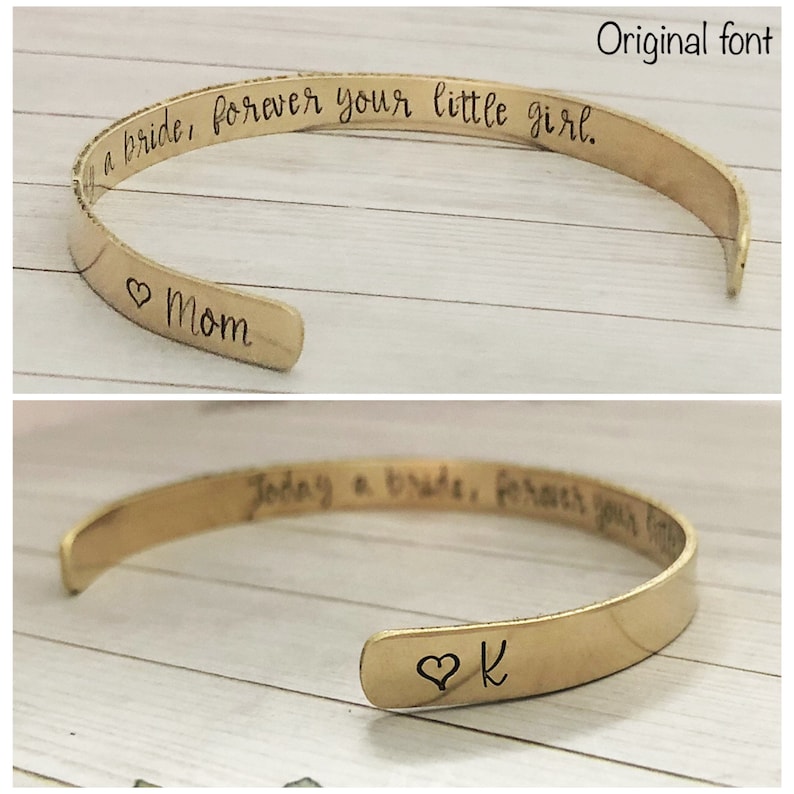 Puede incluir: Dos pulseras de oro con texto grabado. La pulsera superior dice "Today a bride, forever your little girl." y tiene un coraz&oacute;n con "Mom" grabado en la parte inferior. La pulsera inferior dice "Today a bride, forever your" y tiene un coraz&oacute;n con "K" grabado en la parte inferior.