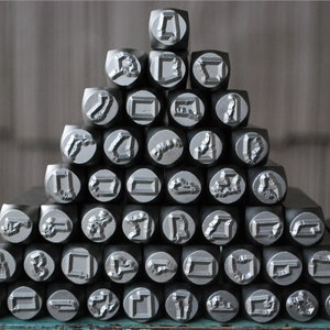 May include: A collection of metal letter stamps arranged in a pyramid shape. The stamps are silver in color and have various letter and symbol designs.