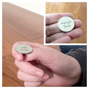 May include: Two silver-coloured tokens with the text "It's Turn" and "Holly's Turn" engraved on them.