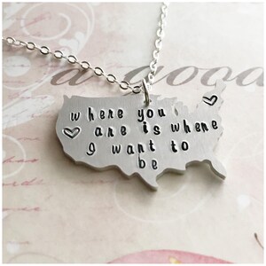 Peut inclure: Collier en argent avec un pendentif en forme des États-Unis. Le pendentif porte le texte "Where you are is where I want to be" avec un symbole de cœur de chaque côté.