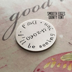May include: A silver round charm with the text "Dad. I'll be seeing you. 09.02.17" engraved on it. The charm has smooth edges and a dainty font.